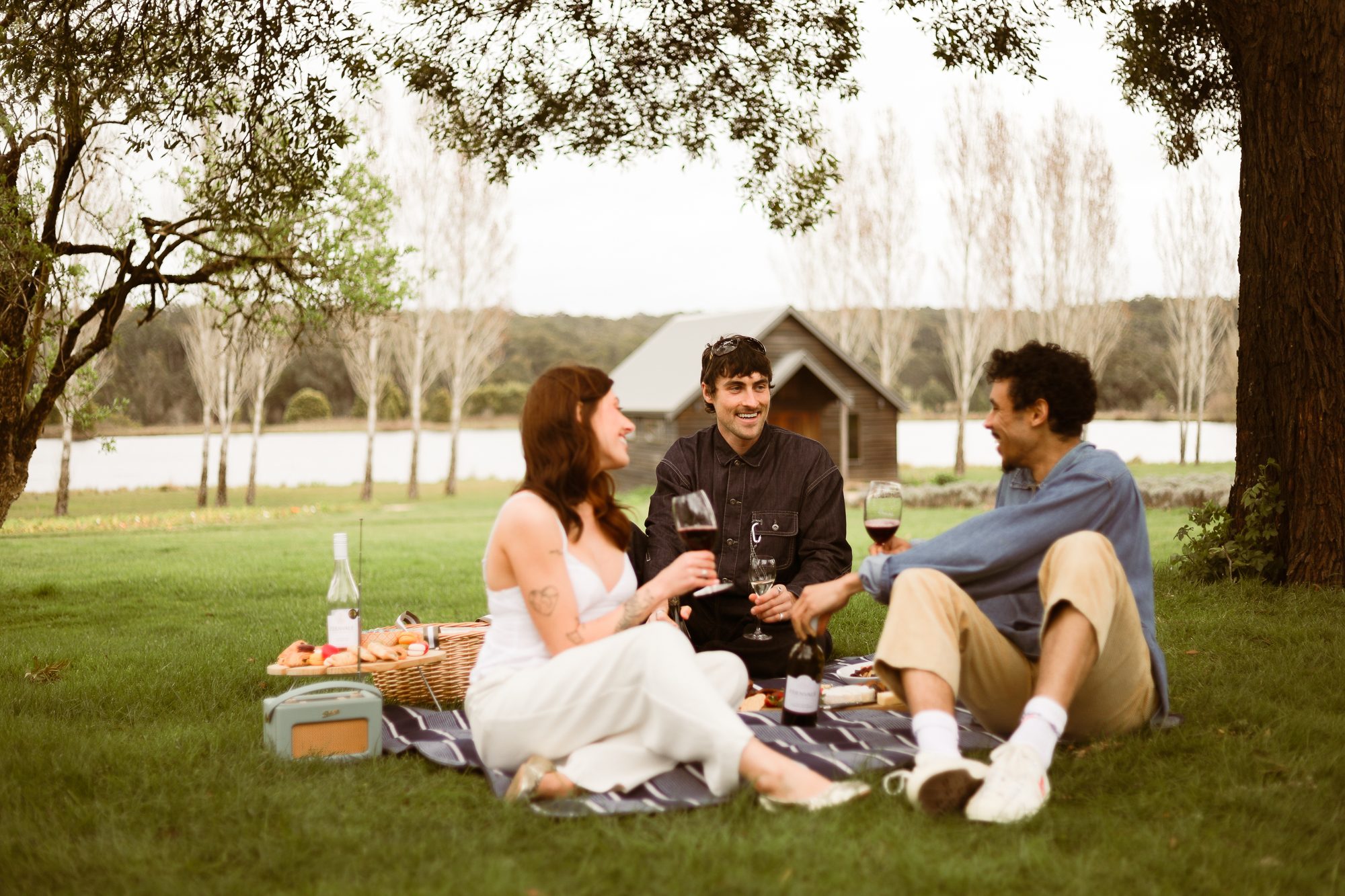 Friends sharing Edenvale wine at a lakeside picnic