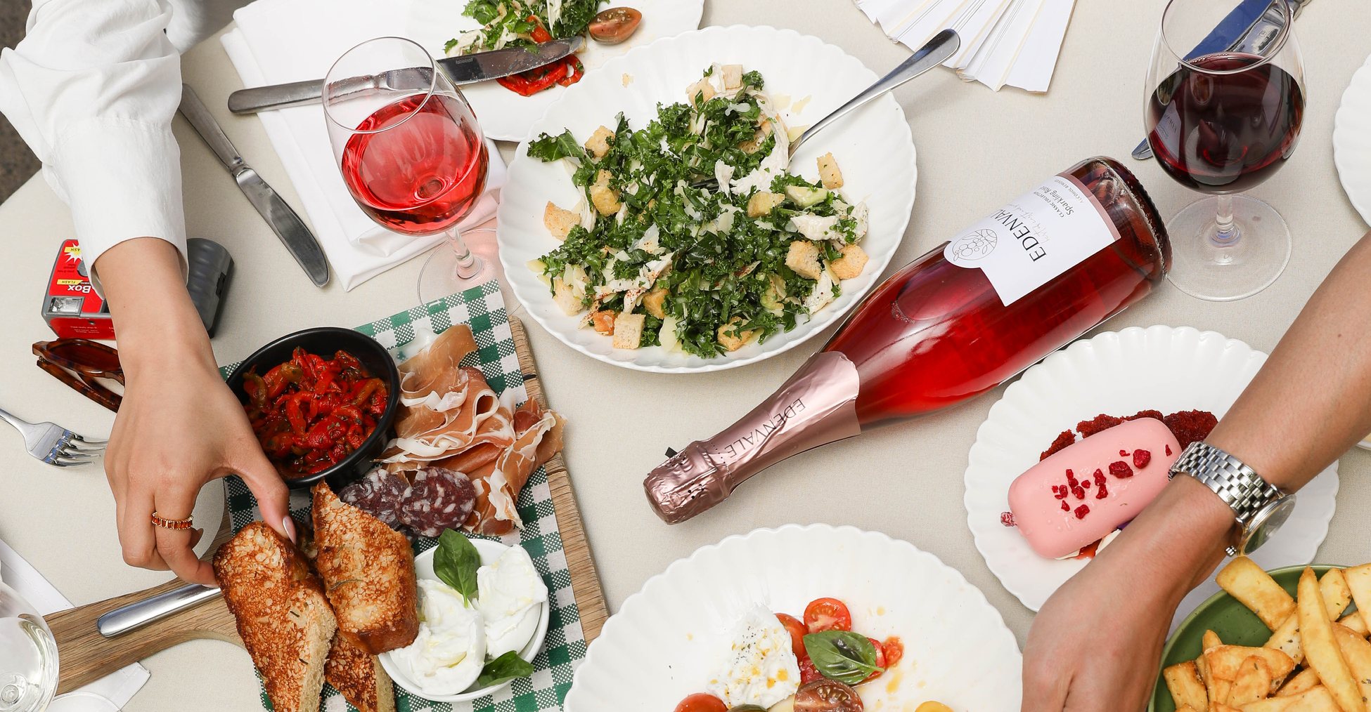 Aerial shot of Edenvale wine bottles lying on a table laden with various dishes of colourful food