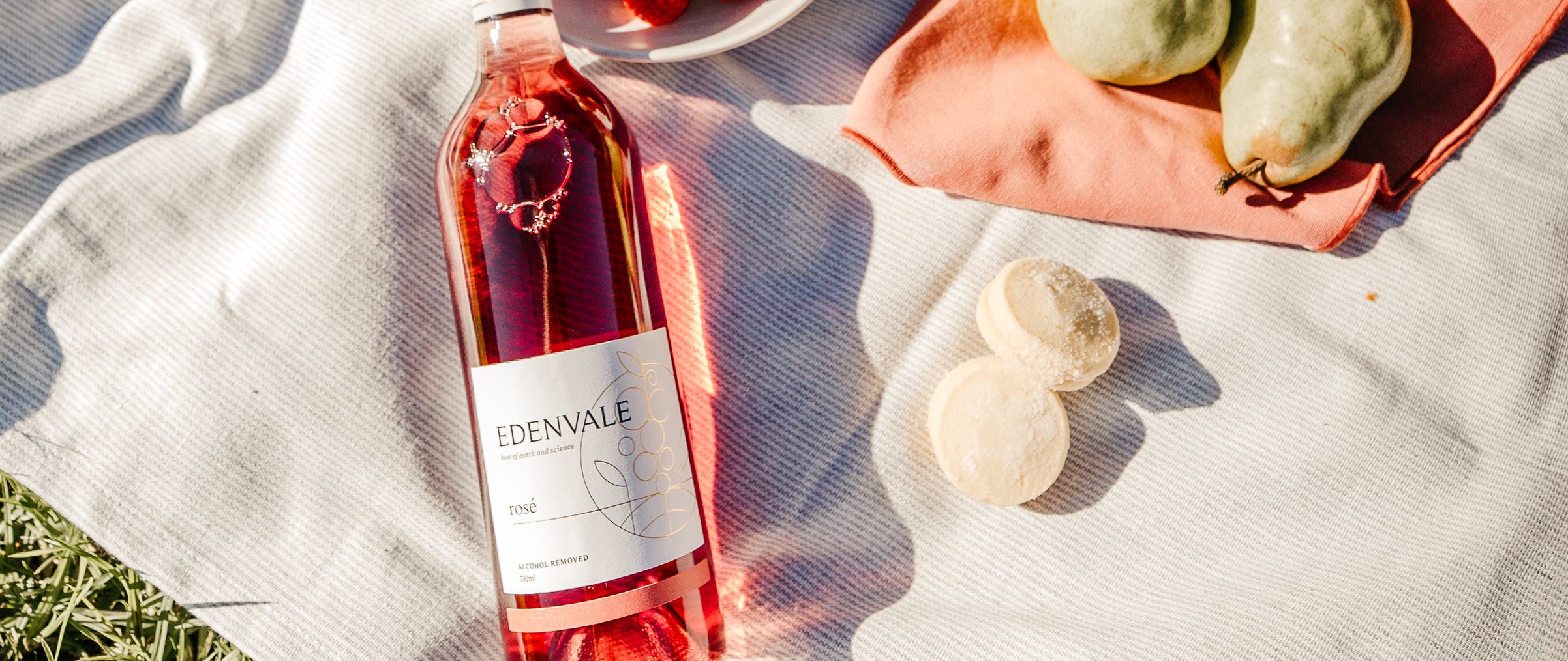 Bottle of Edenvale Rosé wine on a picnic blanket with fruit and food