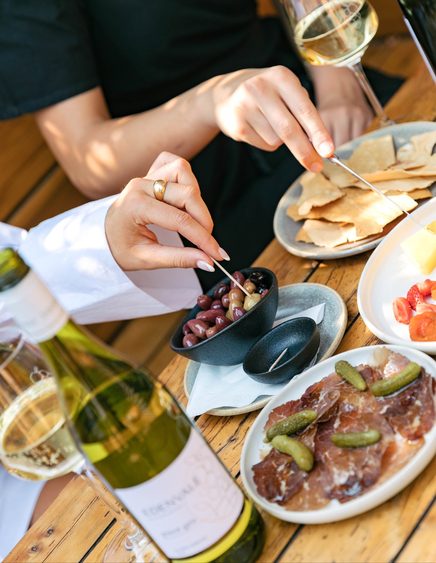 Person eating at a table with wine, tapas, and a bottle of wine.
