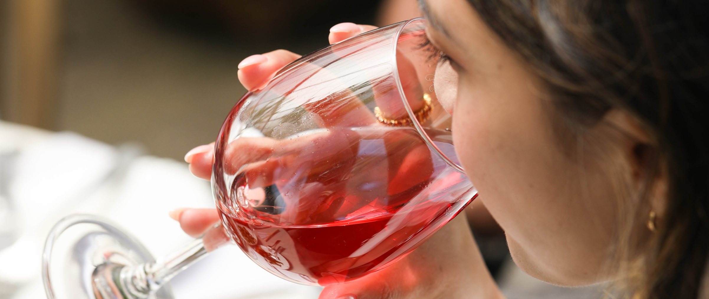 Person drinking non-alcoholic Rosé wine from a glass at a dining table